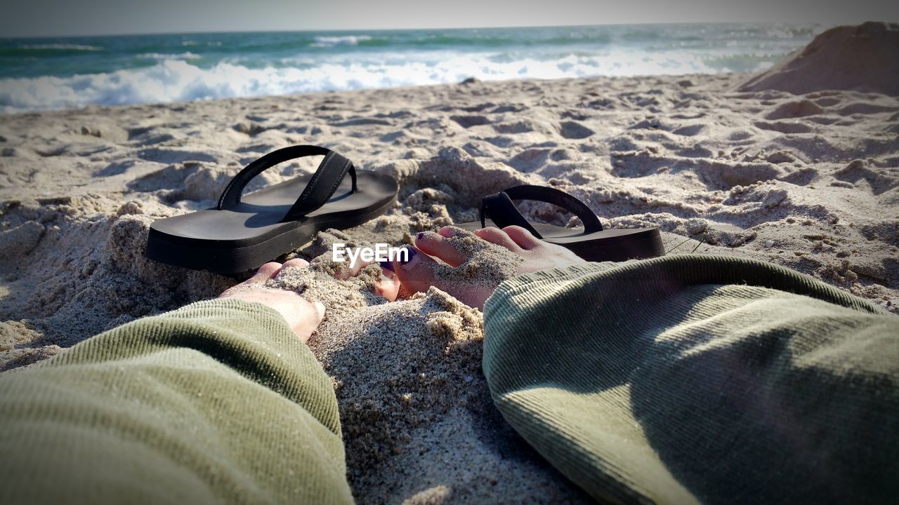 LOW SECTION OF MEN RELAXING ON BEACH