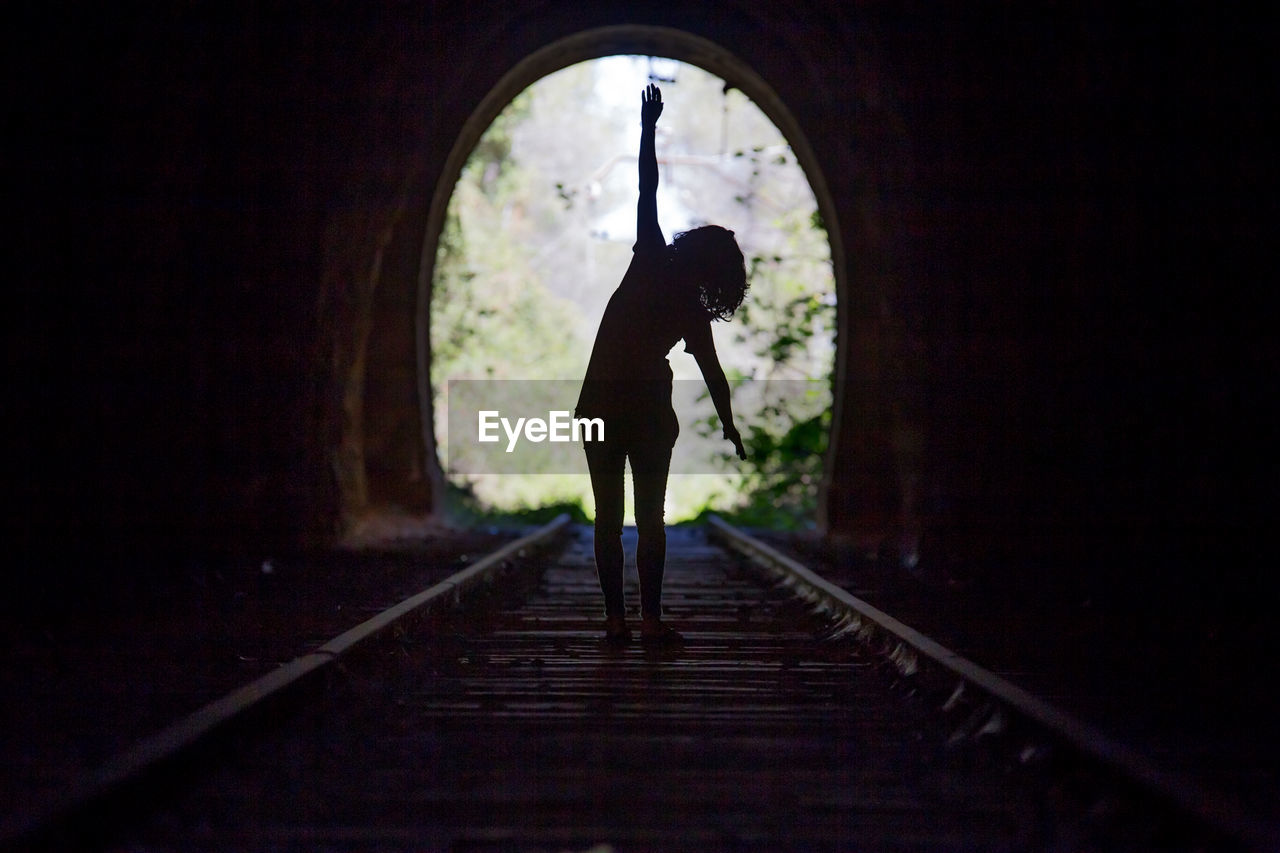 Rear view of silhouette woman walking in tunnel