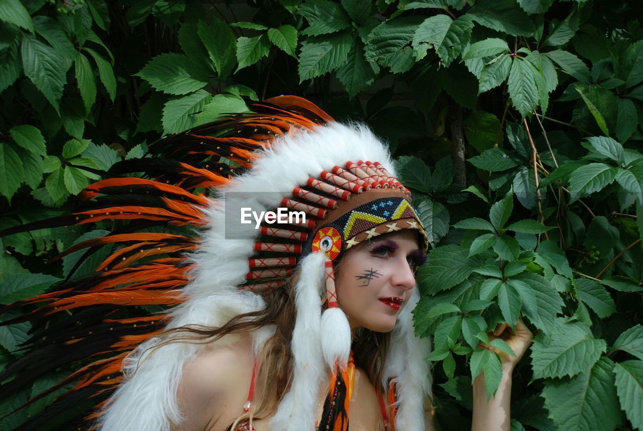 Young woman wearing headdress against plants