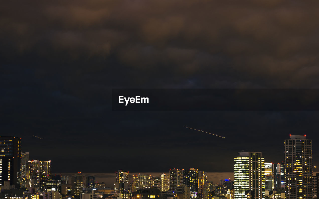 Illuminated buildings in city against sky at night