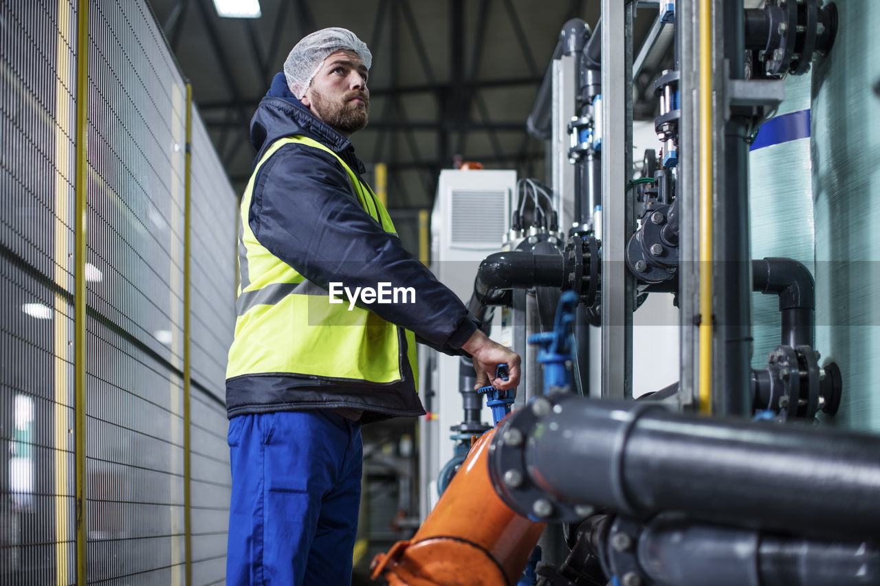 Man turning valve in factory