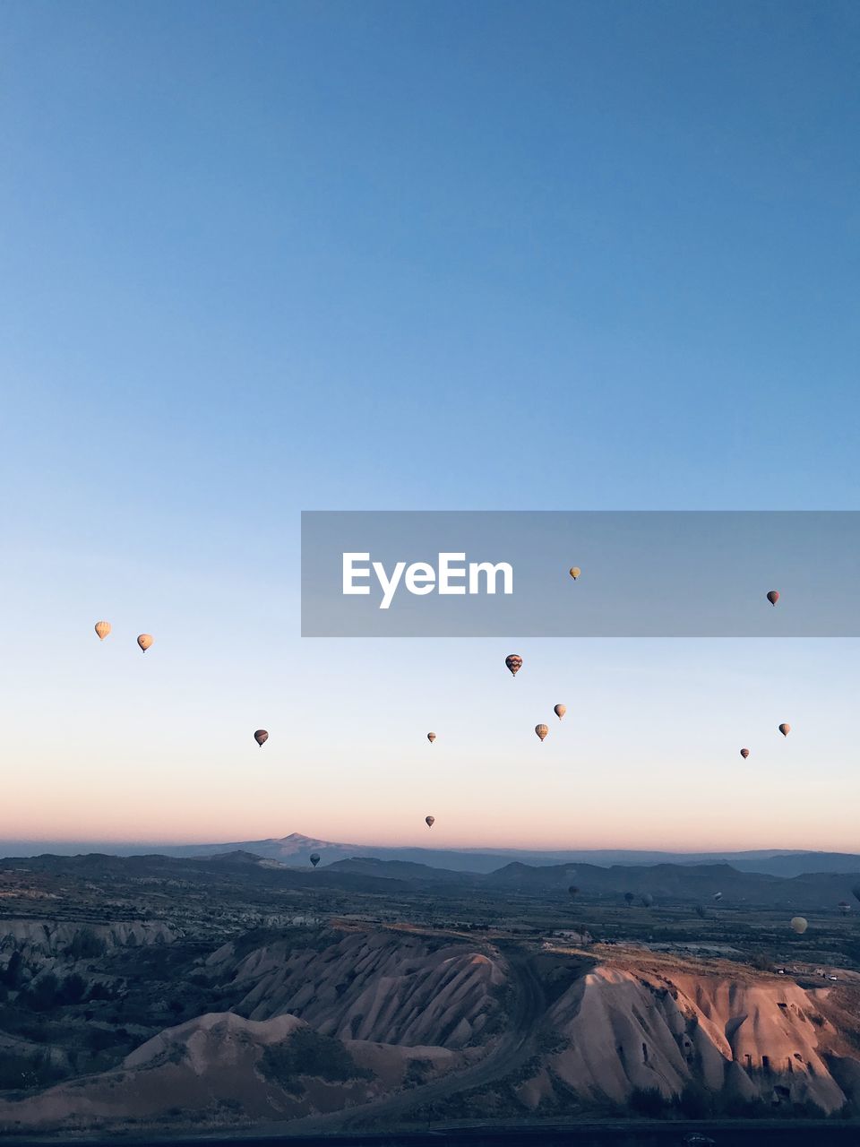 Hot air balloons flying over landscape against sky during sunset