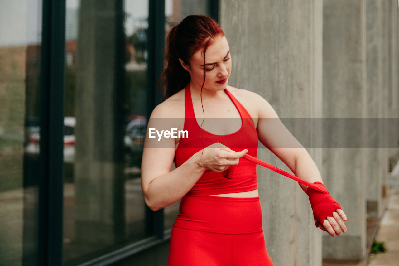 Young female boxer, wrapping wrist for boxing in brooklyn street.