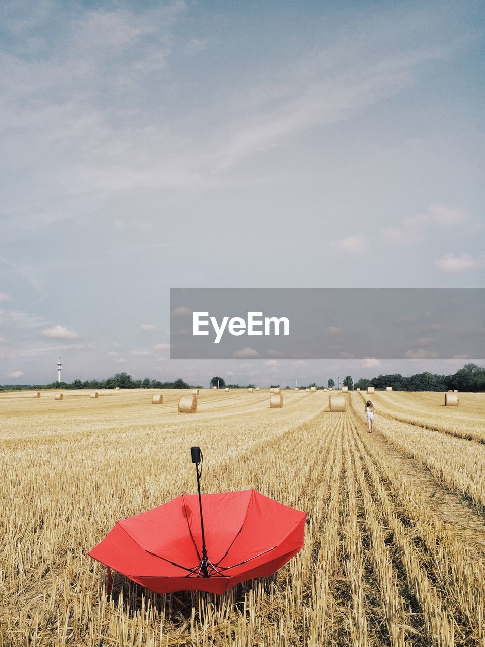 Red umbrella on agricultural field against sky
