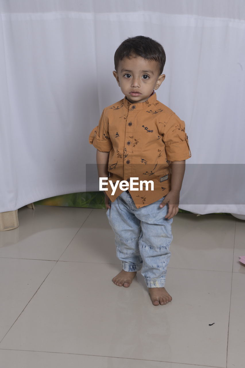 Portrait of boy standing on floor at home