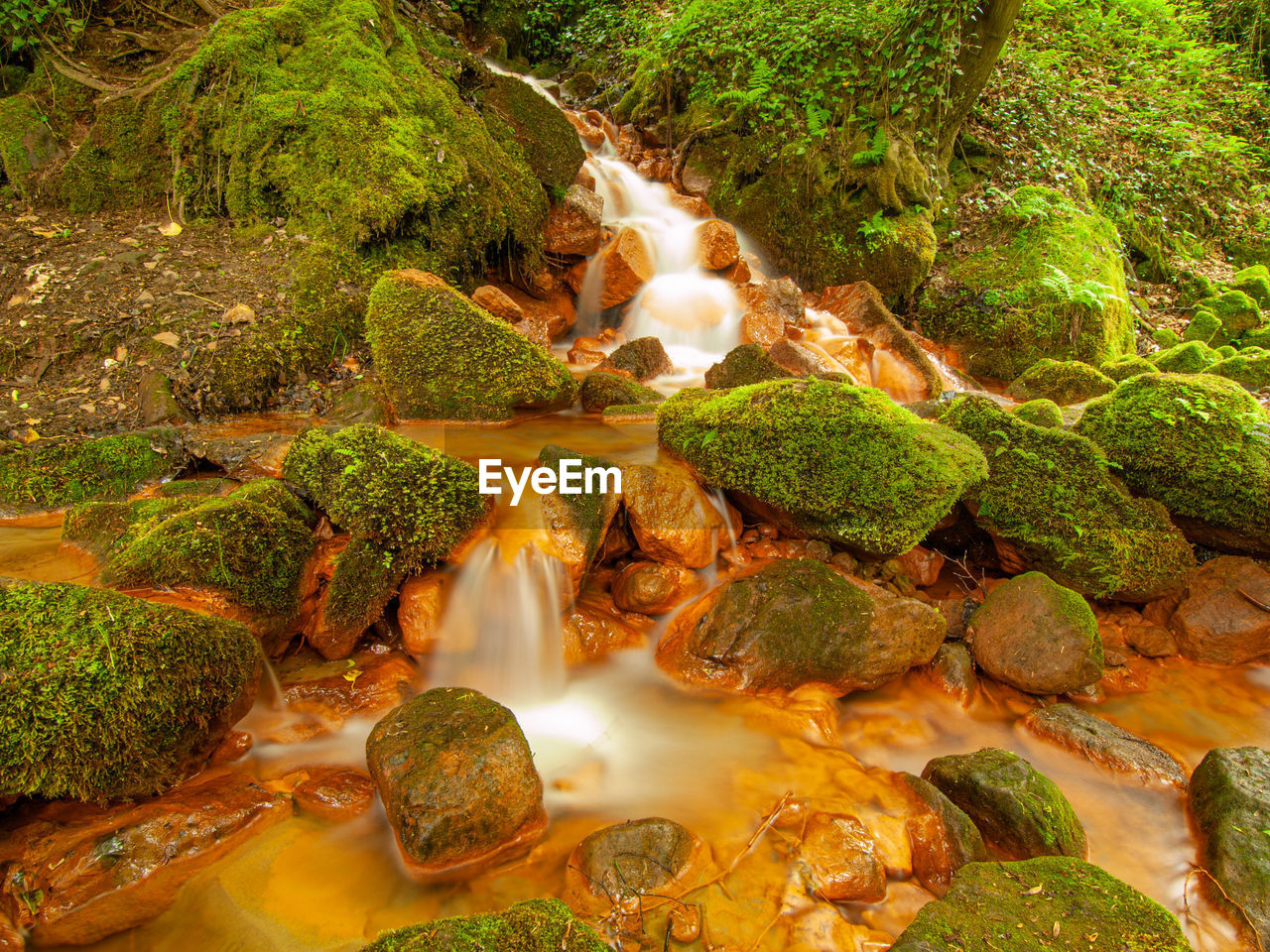 View of mineral waterfall in forest, falling streams over stone with ferric surface