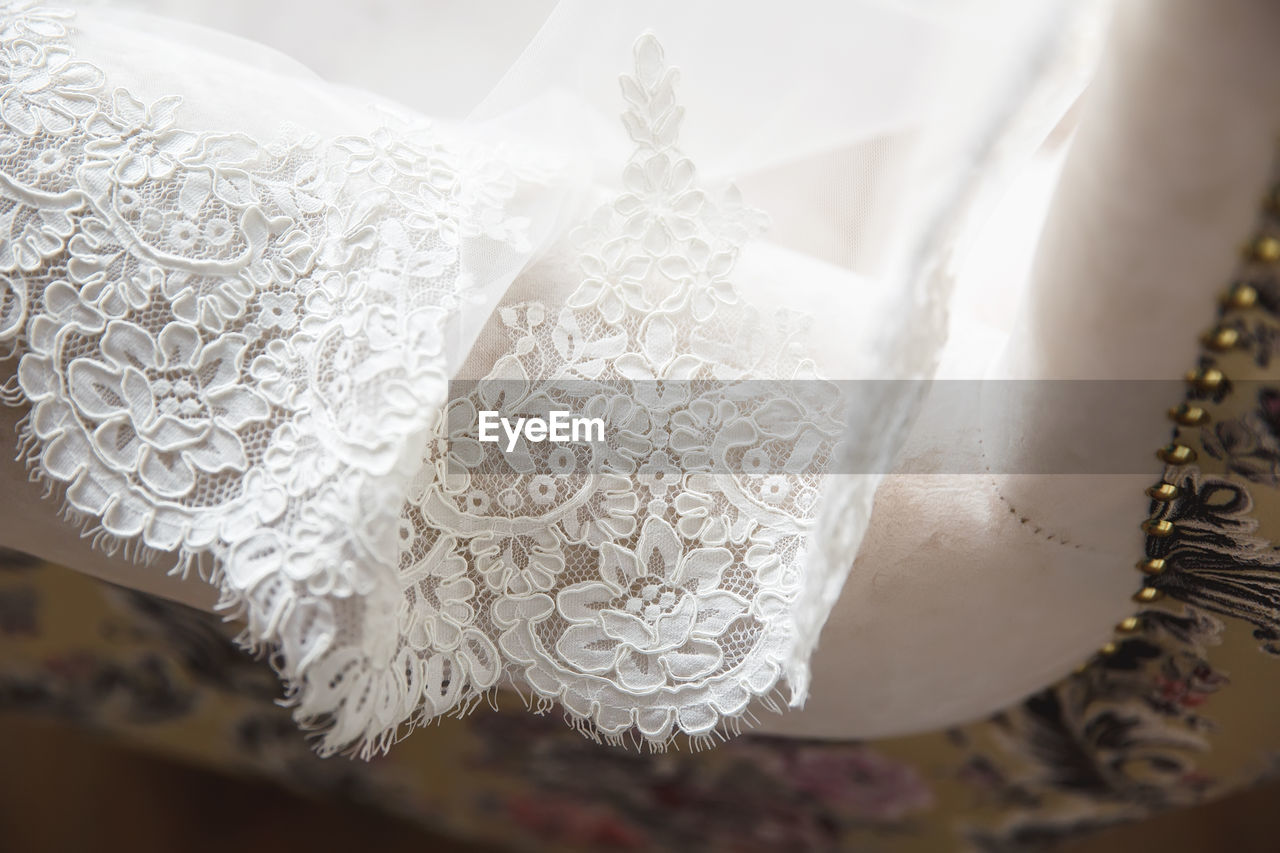 lace, wedding dress, fashion accessory, wedding, clothing, celebration, gown, bridal clothing, lace - textile, white, event, dress, indoors, fashion, close-up, life events, bride, veil, textile, pattern, elegance, wealth, luxury, selective focus, focus on foreground, jewelry, decoration, newlywed, flower