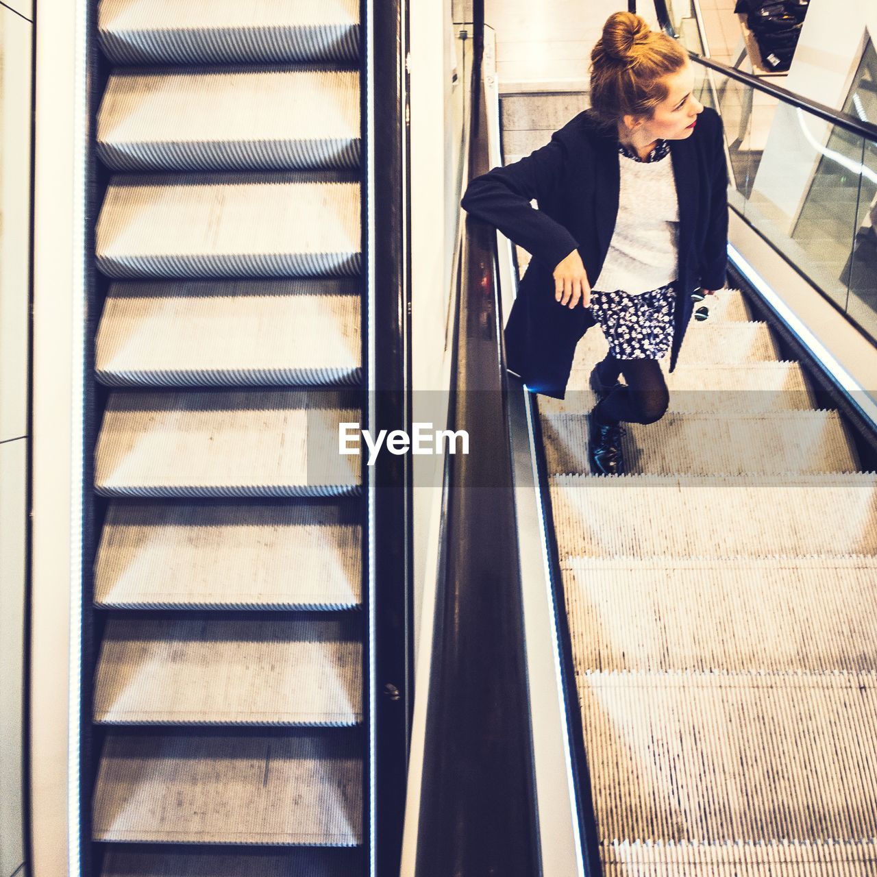 High angle view of woman standing on escalator at shopping mall