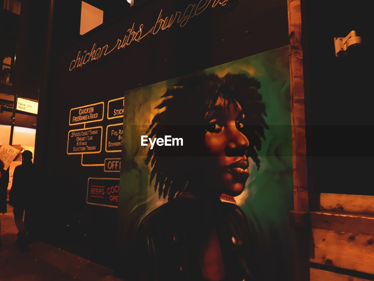 PORTRAIT OF WOMAN STANDING BY WINDOW IN ILLUMINATED BUILDING