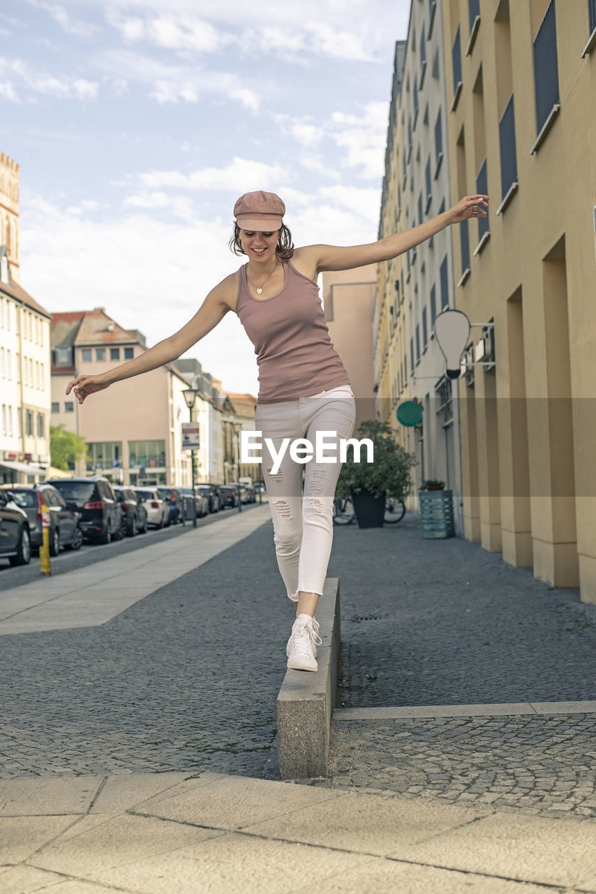 full length of young woman exercising on footpath in city