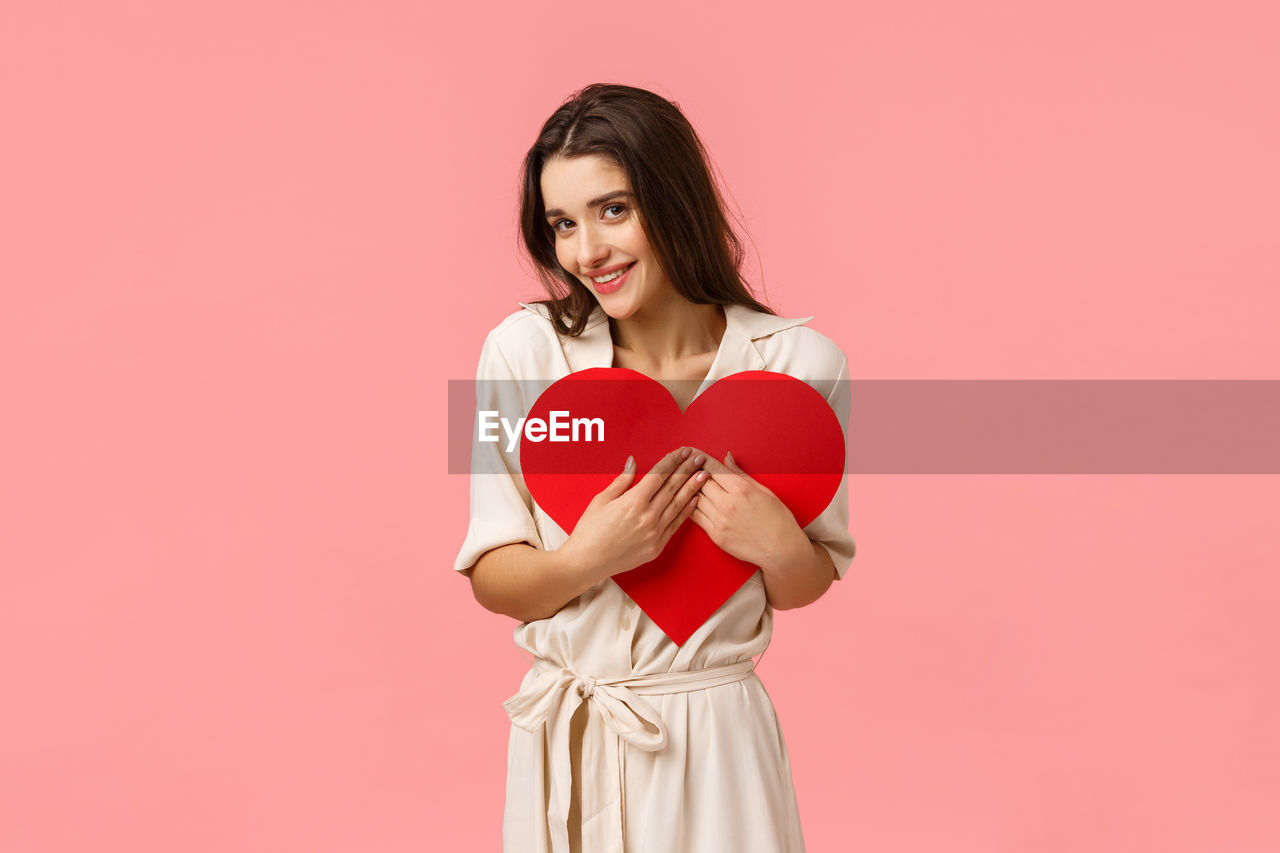 PORTRAIT OF A SMILING YOUNG WOMAN OVER RED BACKGROUND