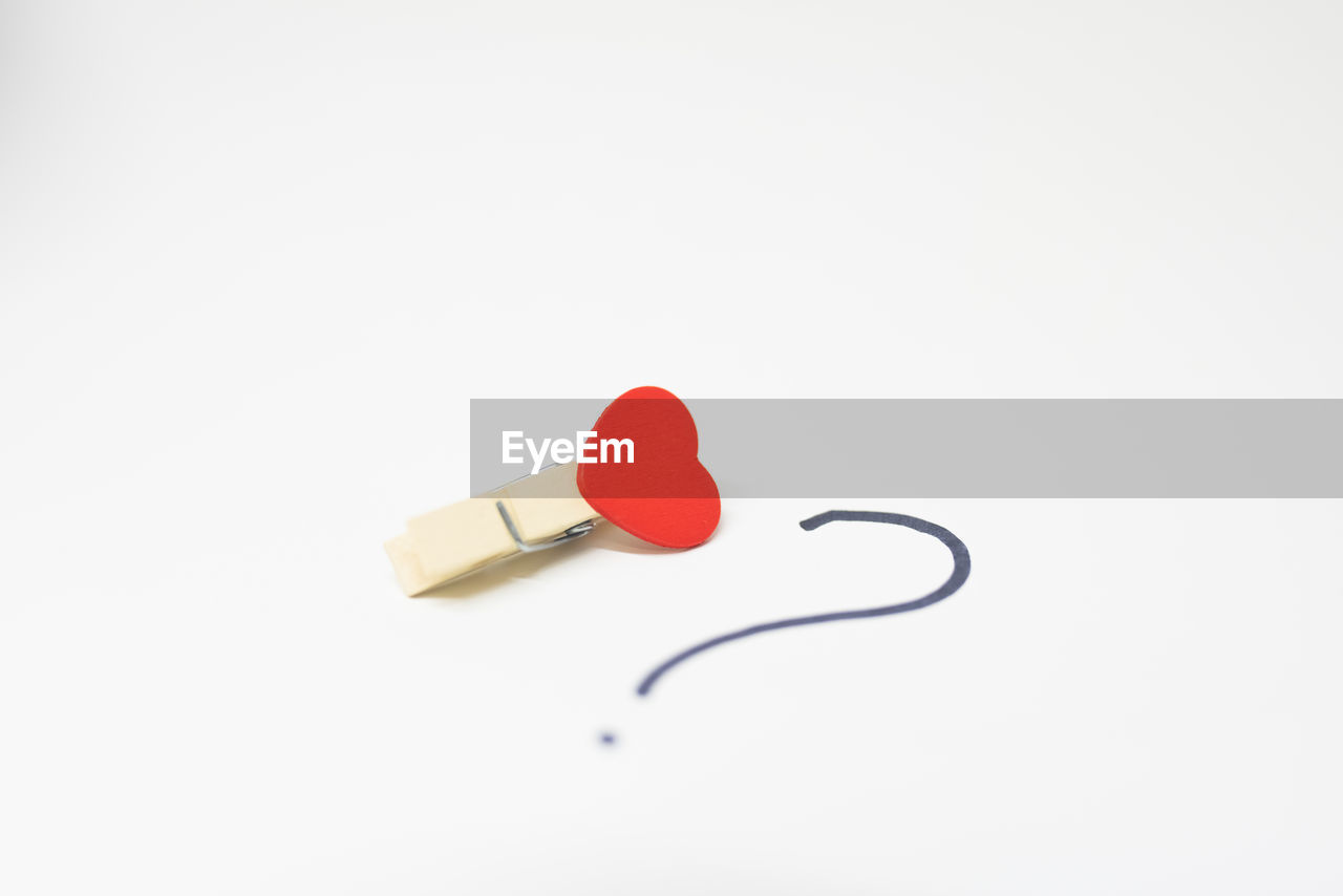 Close-up of heart shape and clothespin over white background