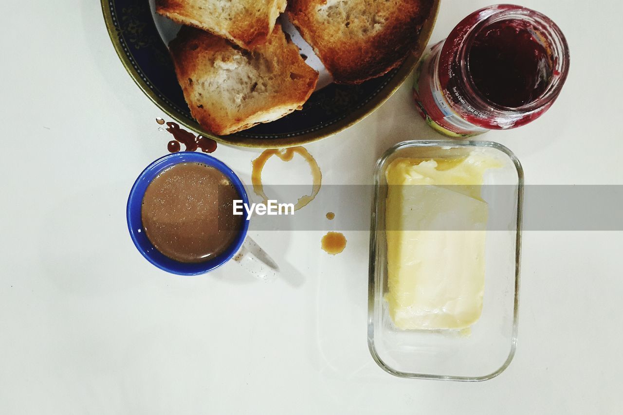 Directly above shot of coffee cup with toasted breads and jam