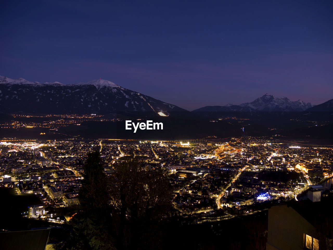 HIGH ANGLE VIEW OF ILLUMINATED BUILDINGS IN CITY AGAINST SKY