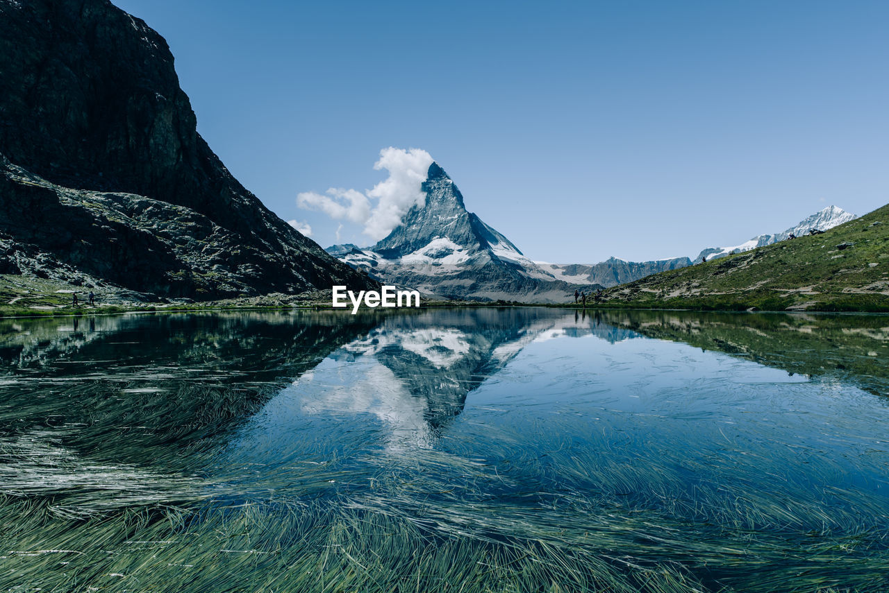 Scenic view of lake and mountains against blue sky