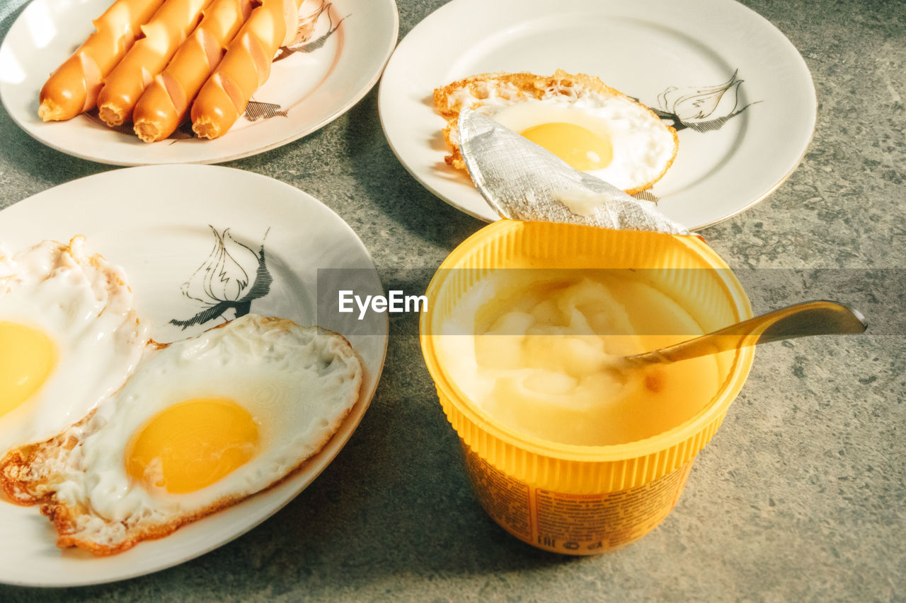 Homemade simple breakfast set of fried eggs and sausages on table in the morning.