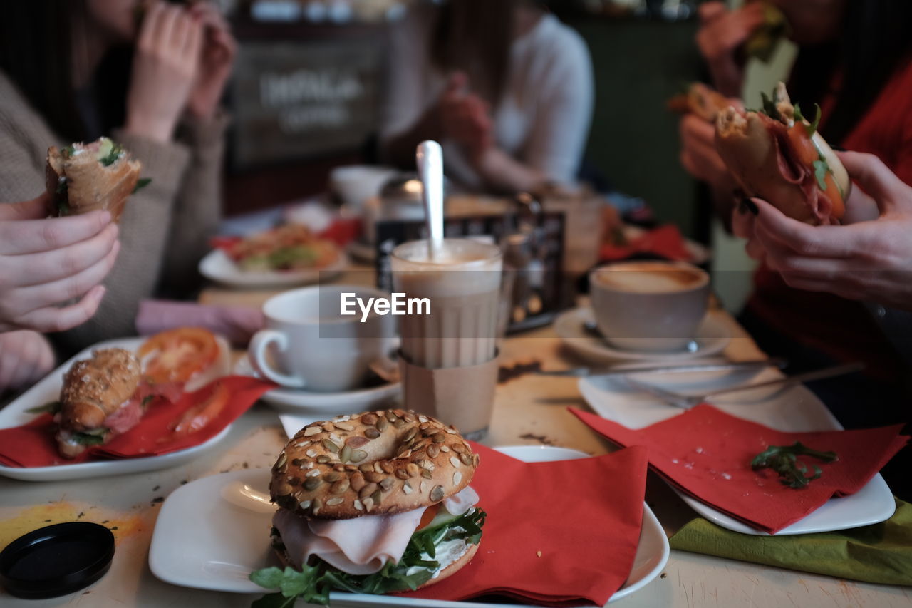 Cropped image of people eating bagels at restaurant