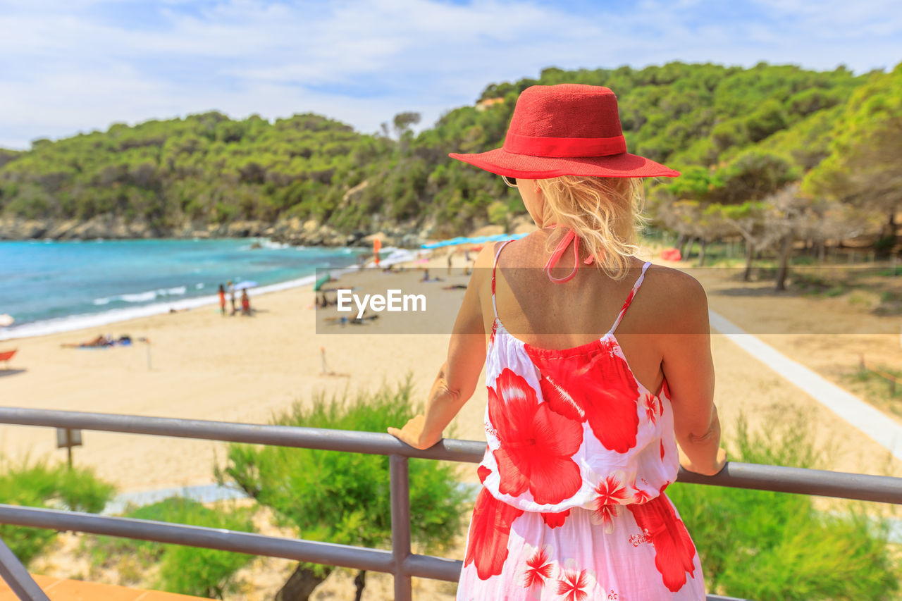 Rear view of woman standing by railing against sea