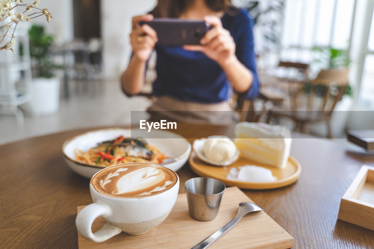 Midsection of woman photographing food using phone