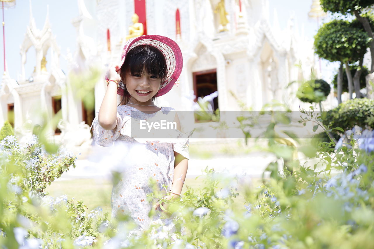 Portrait of cute girl standing by plants