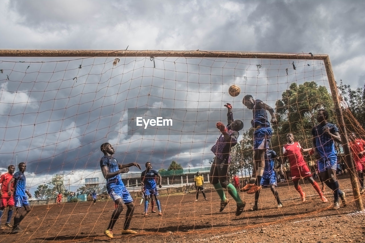 People playing soccer against cloudy sky