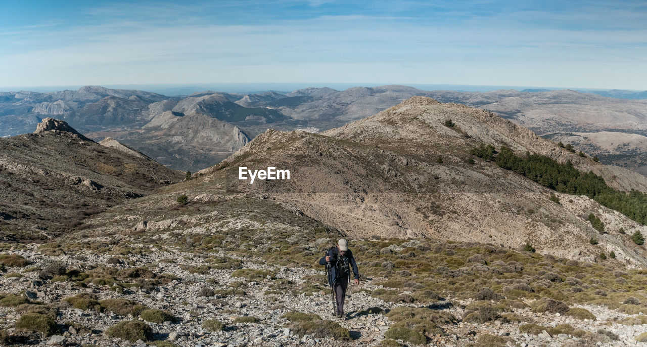 MAN ON MOUNTAIN AGAINST SKY