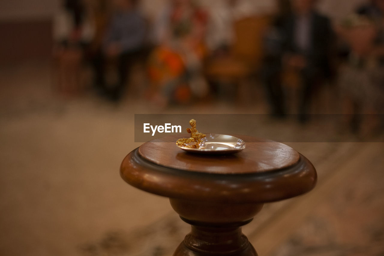 Wedding rings lie in golden saucer. stand made of wood at wedding ceremony.