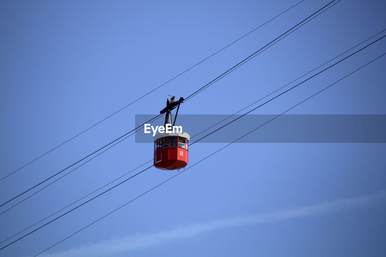 Low angle view of overhead cable car against blue sky