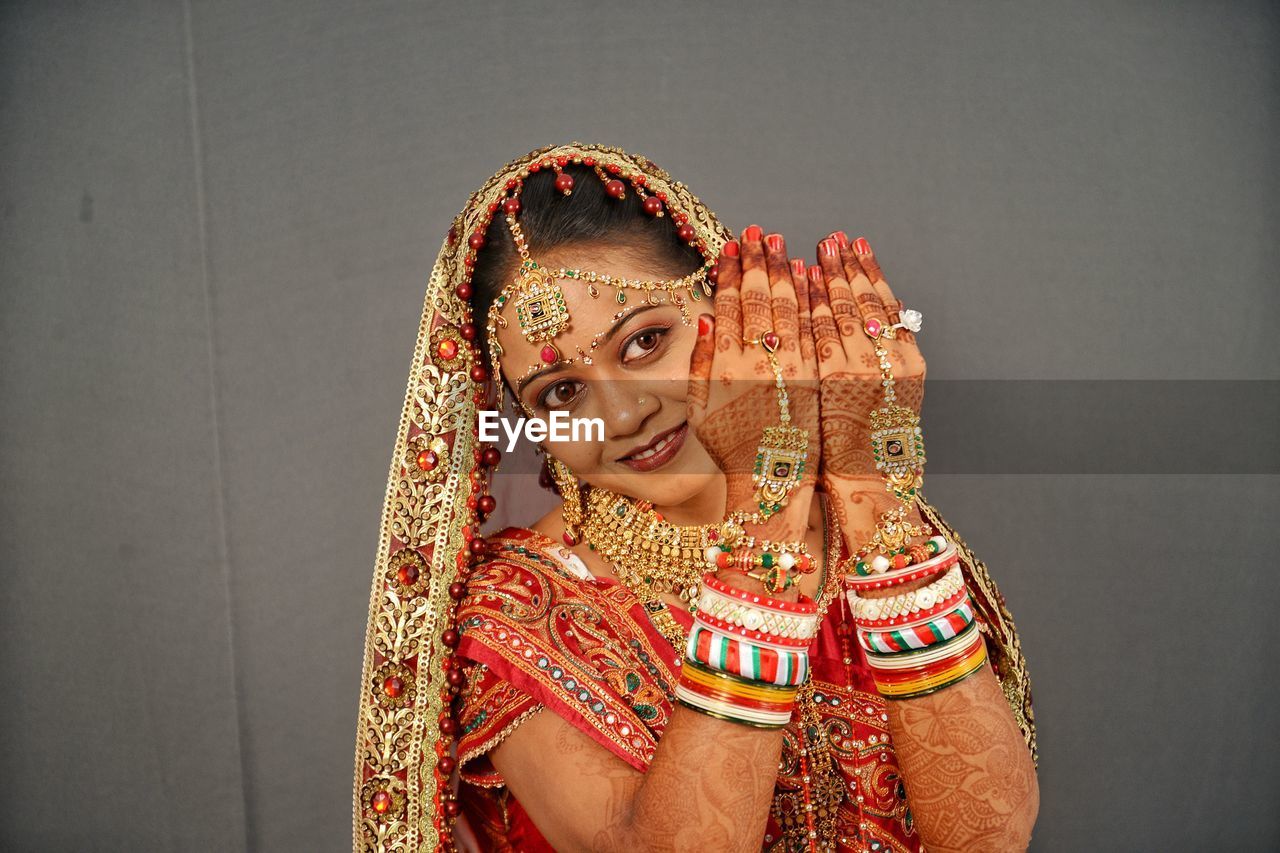 Close-up of smiling young bride gesturing against wall at home