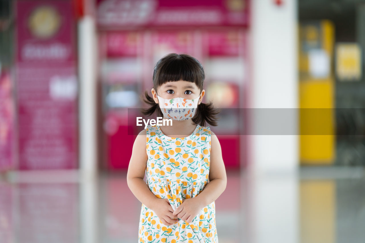 PORTRAIT OF CUTE GIRL STANDING AGAINST WALL