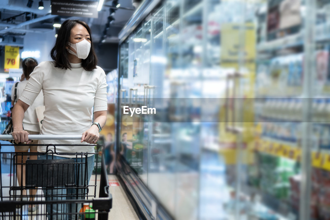 Young asian woman kid with face mask in supermarket. concept for life in outbreak and new normal.