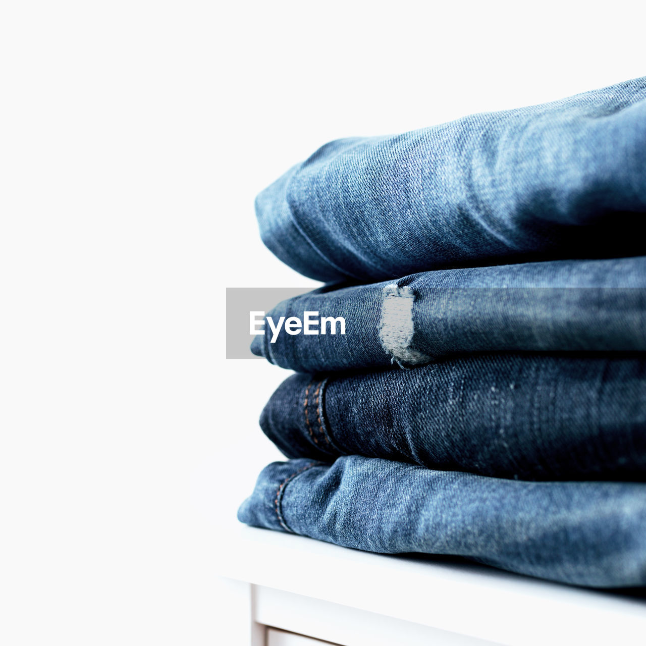 Stack of different blue denim jeans trousers on the table. photo of stacked various shade jeans