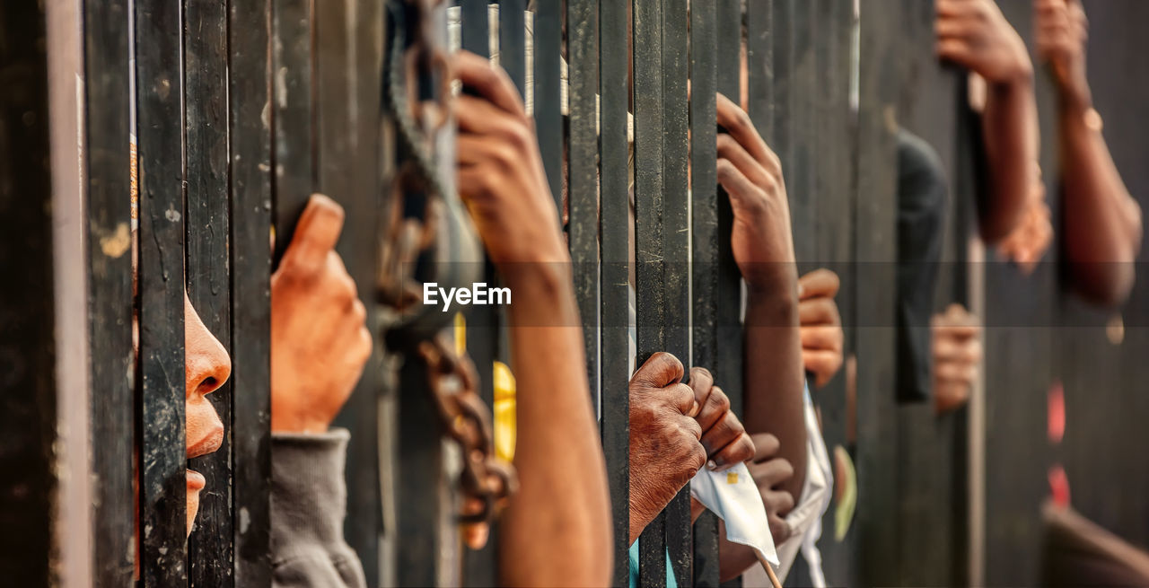 Hands of people holding fence