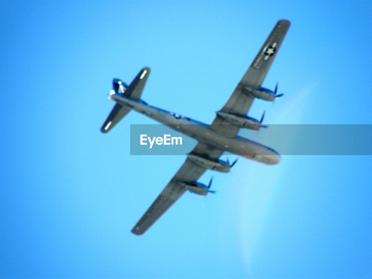 LOW ANGLE VIEW OF AIRPLANE FLYING IN CLEAR BLUE SKY