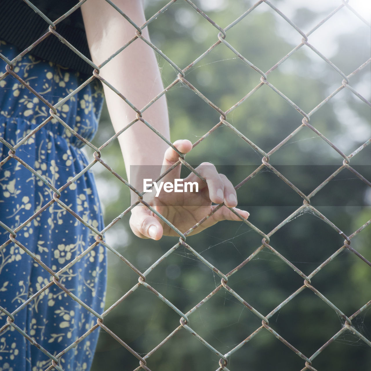 Midsection of woman standing by chainlink fence