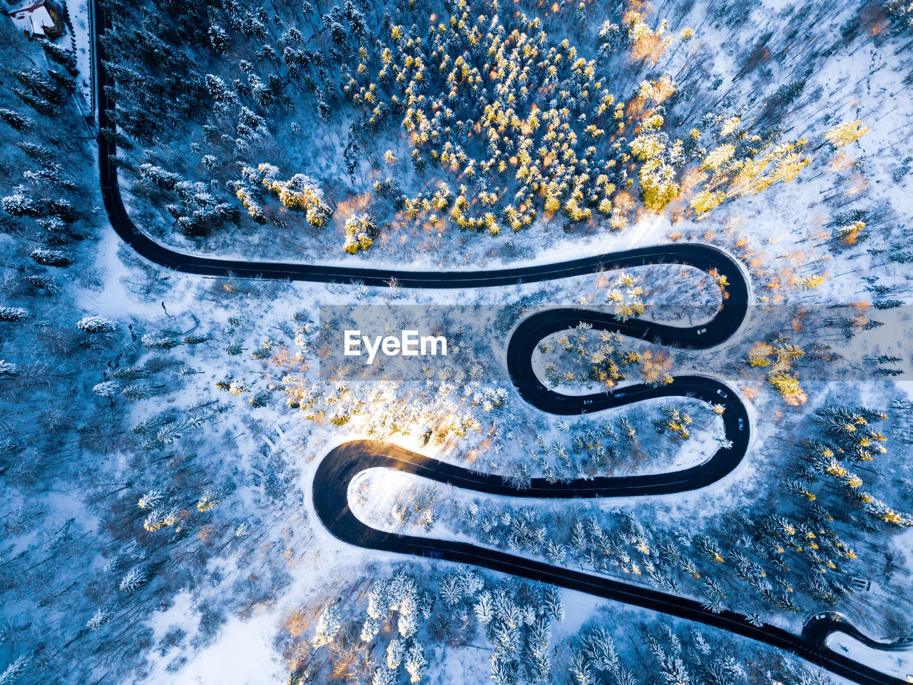 Winding road from high mountain pass, in winter. aerial view by drone . romania