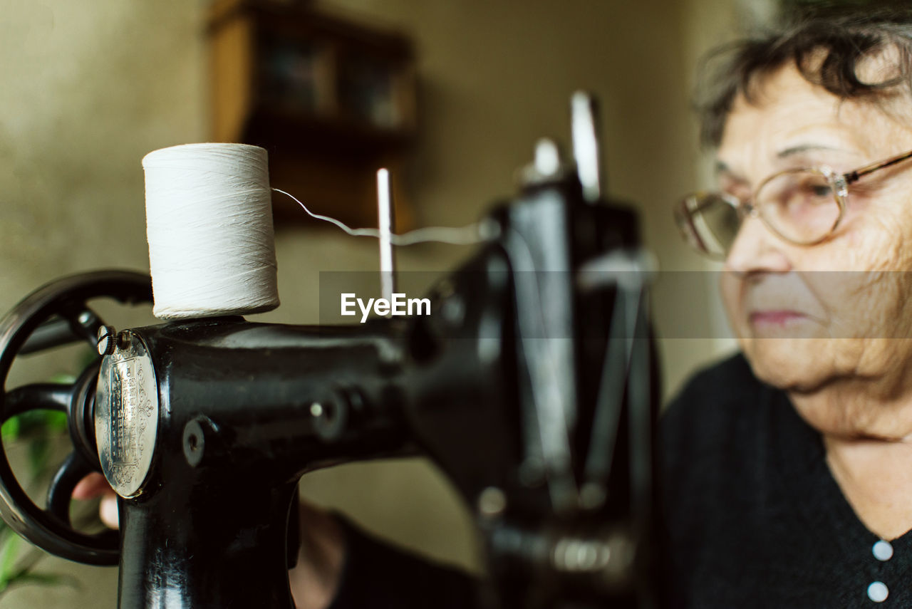 Close-up of senior woman with sewing machine at home