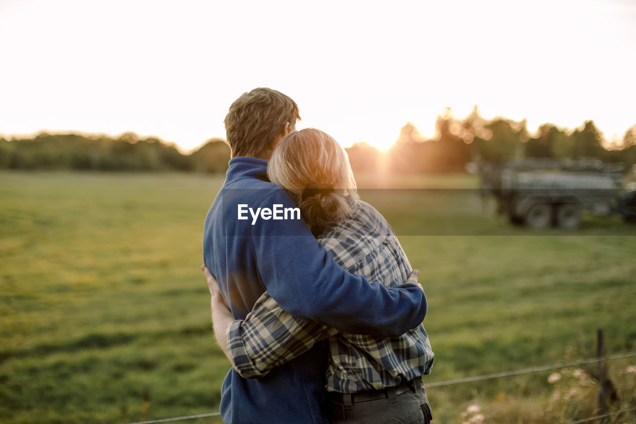 Couple hugging each other on field during sunset