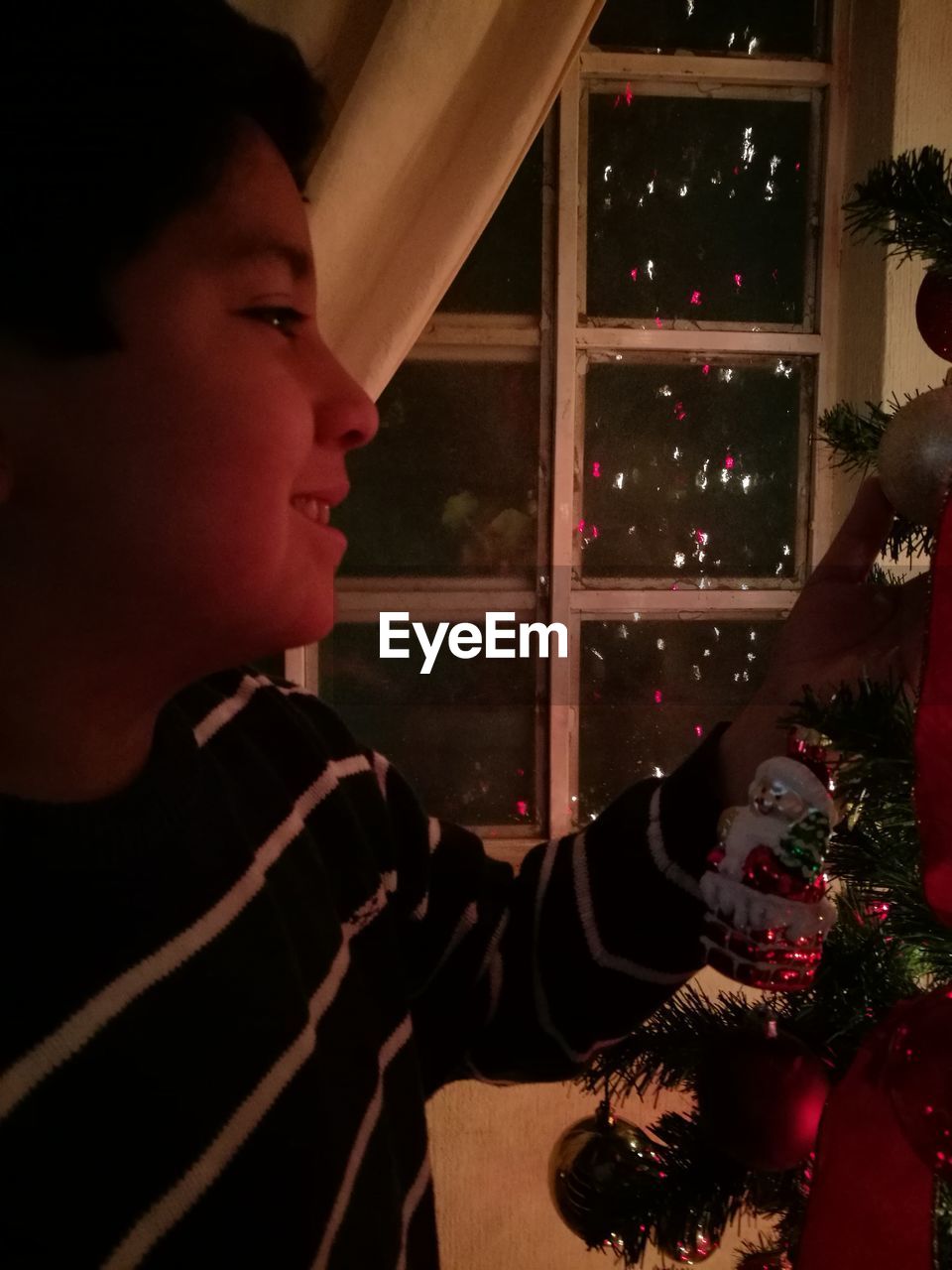 Close-up of boy with christmas tree at home