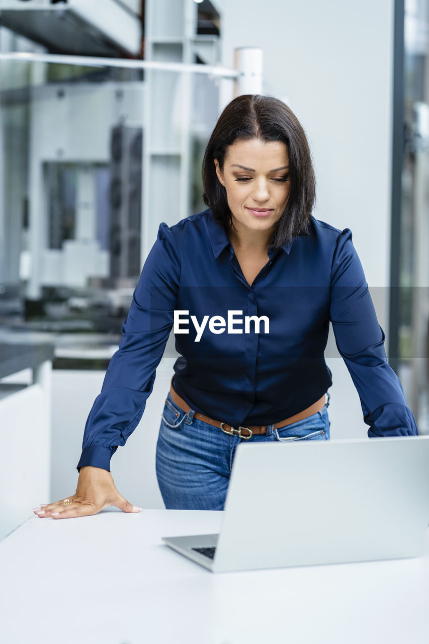 Smiling businesswoman looking at laptop on table