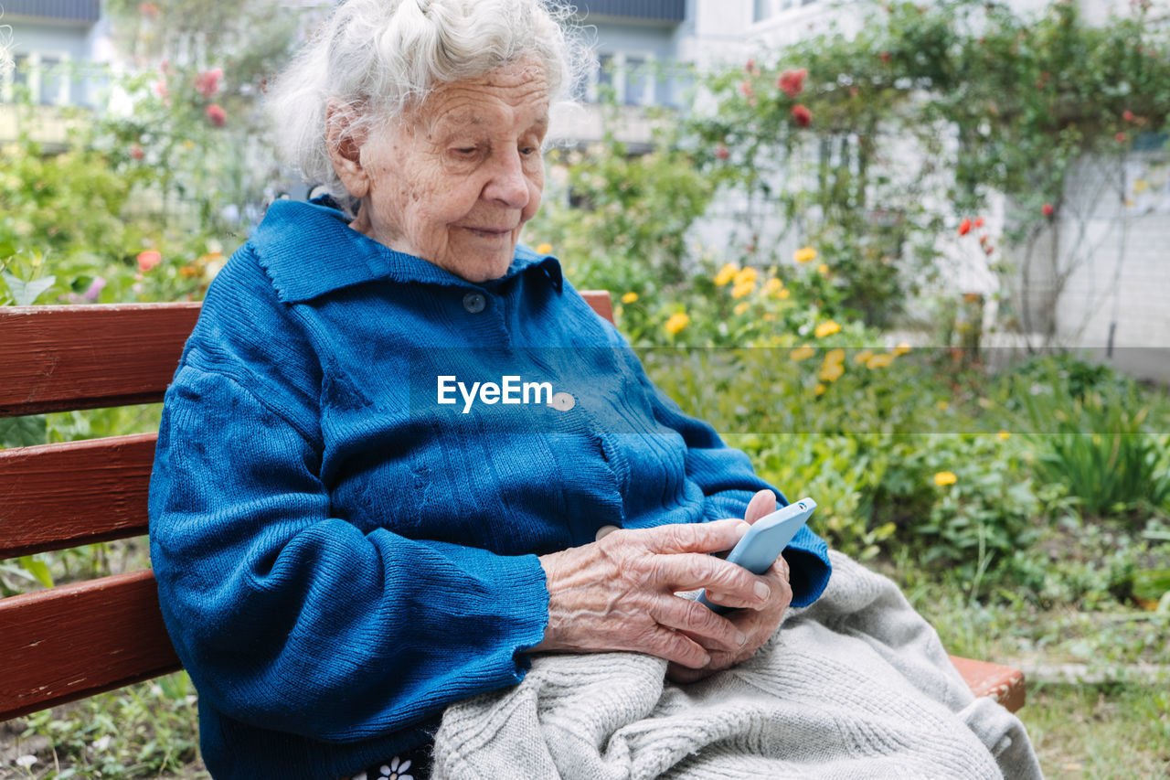 Senior mature woman, grandmother holding phone, using mobile device apps, looking at screen