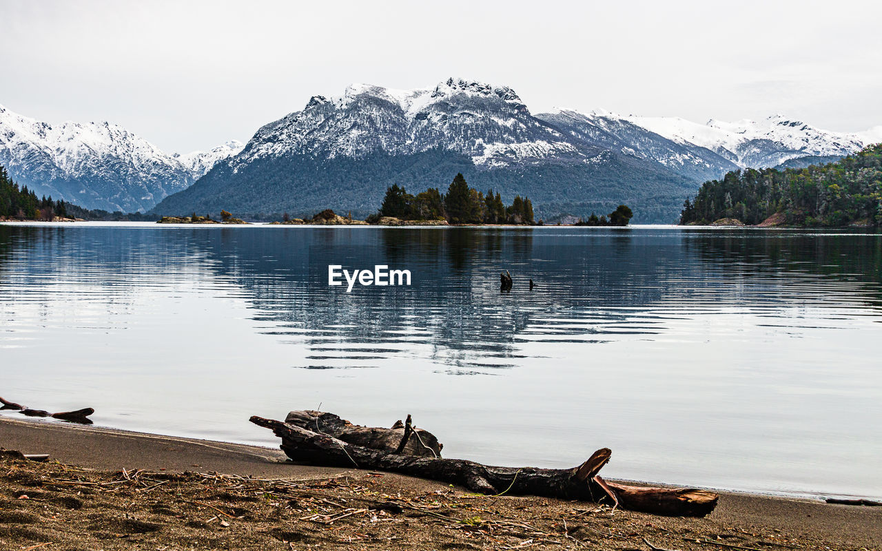 Scenic view of lake by snowcapped mountains against sky