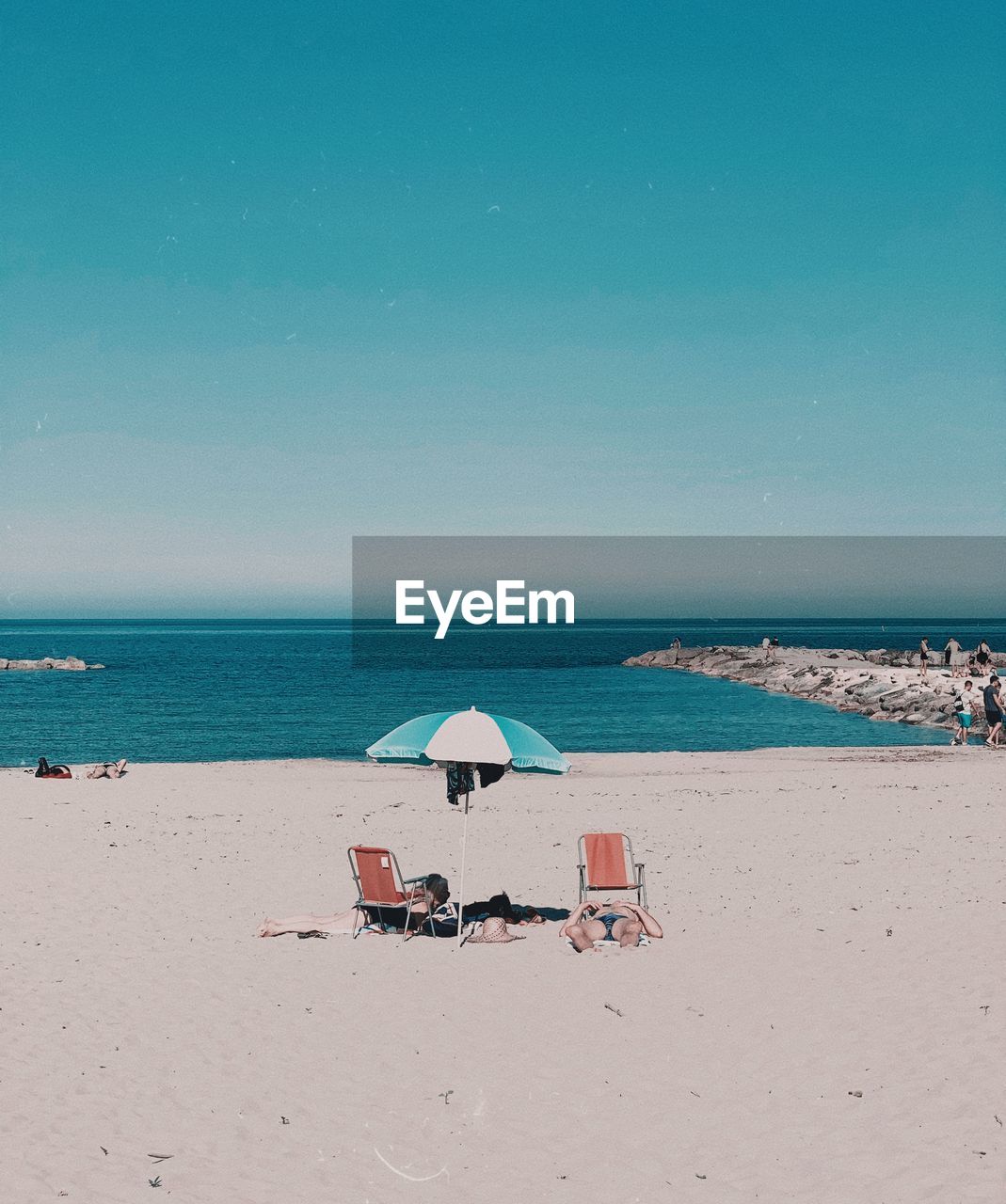 People relaxing at beach against sky