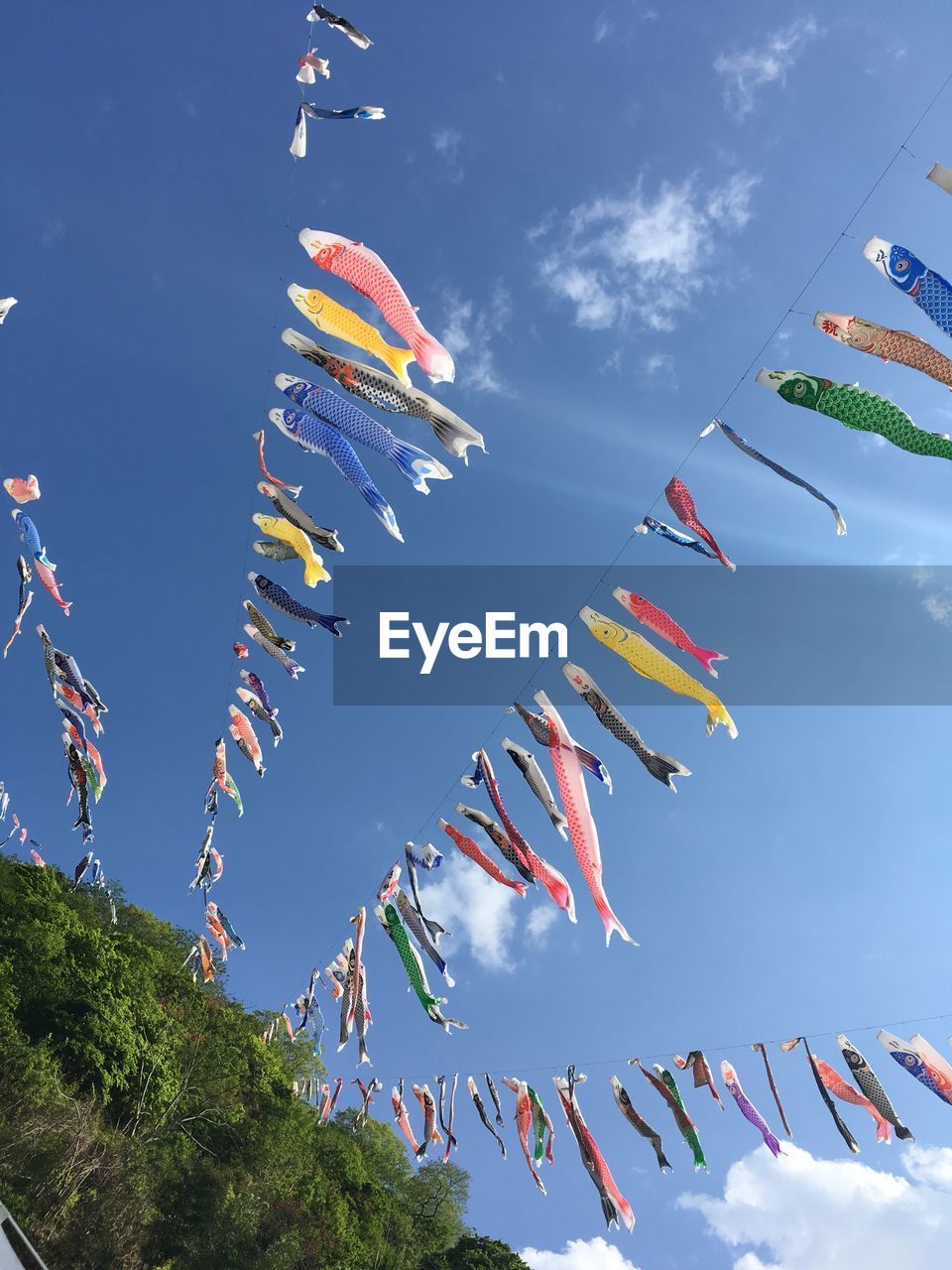 Low angle view of fish shaped buntings hanging against blue sky