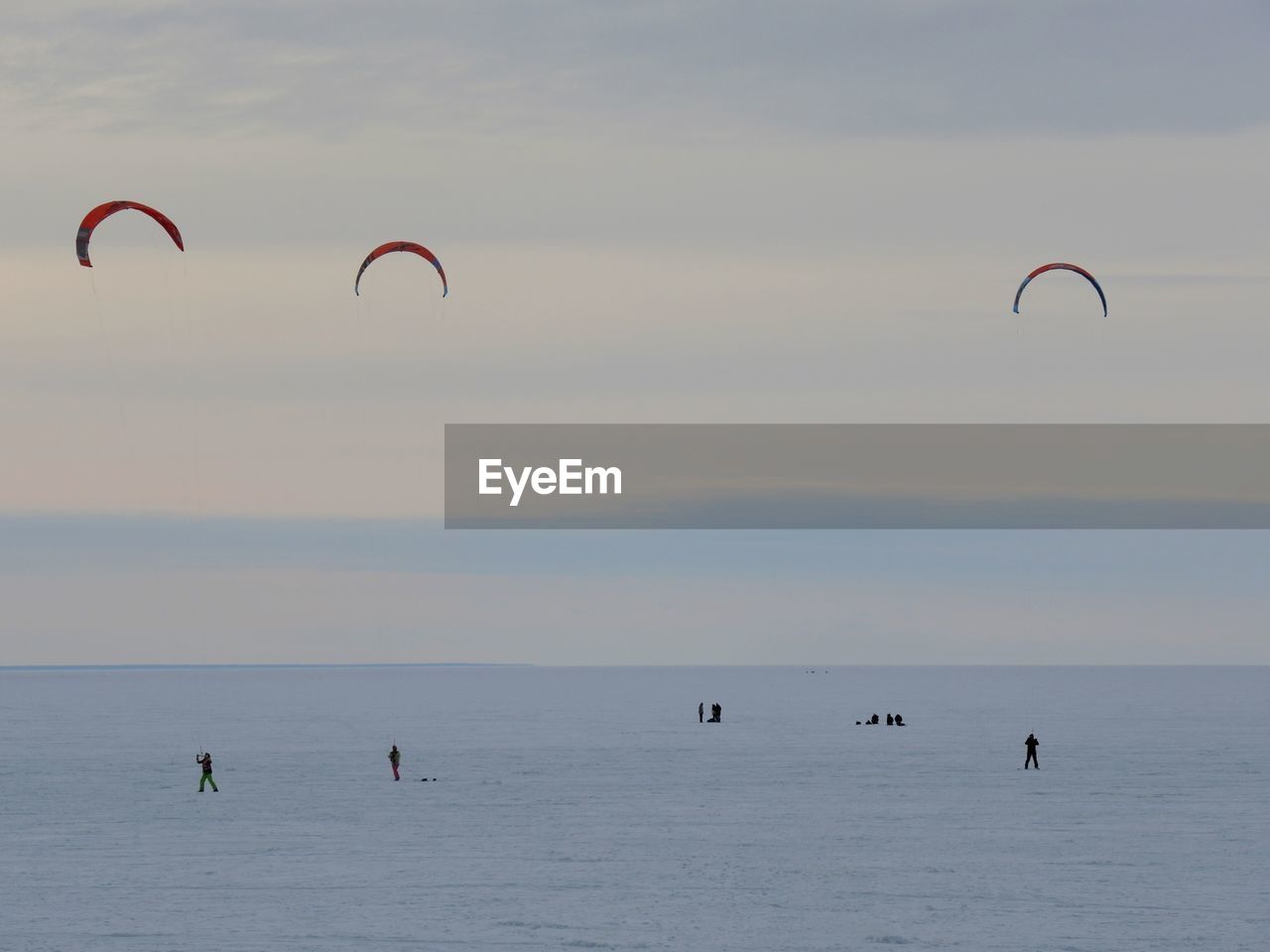 People in sea against sky during sunset