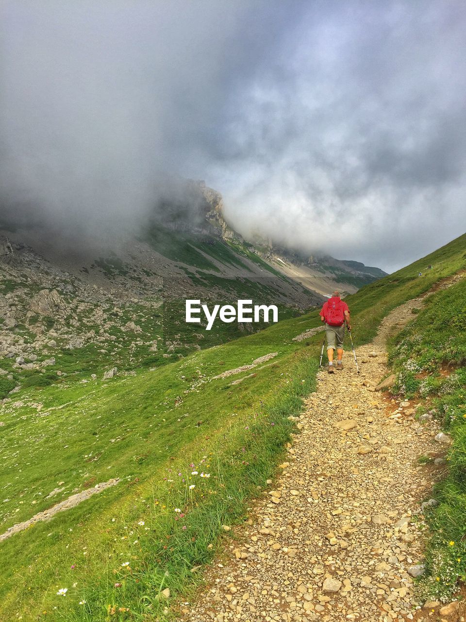 Rear view of male hiker hiking on mountain against sky