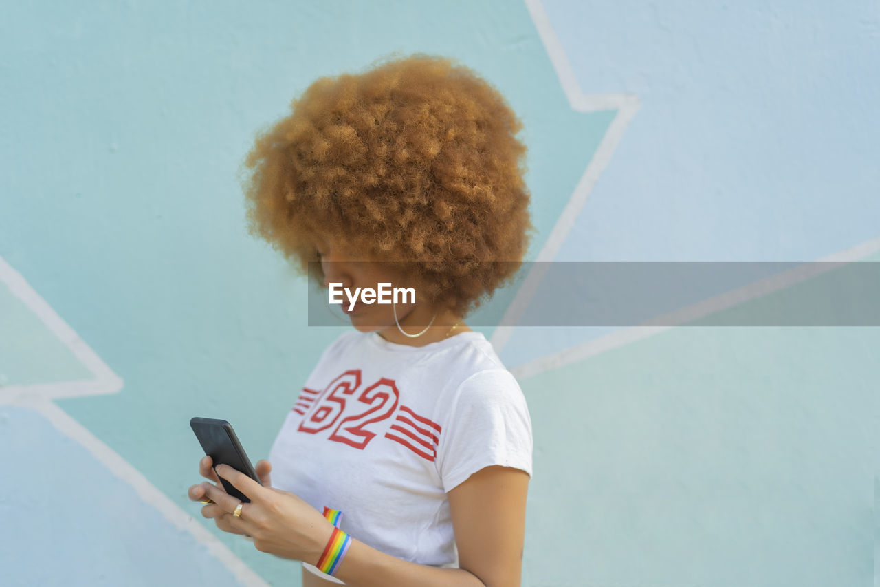 Woman with afro hair using her smartphone
