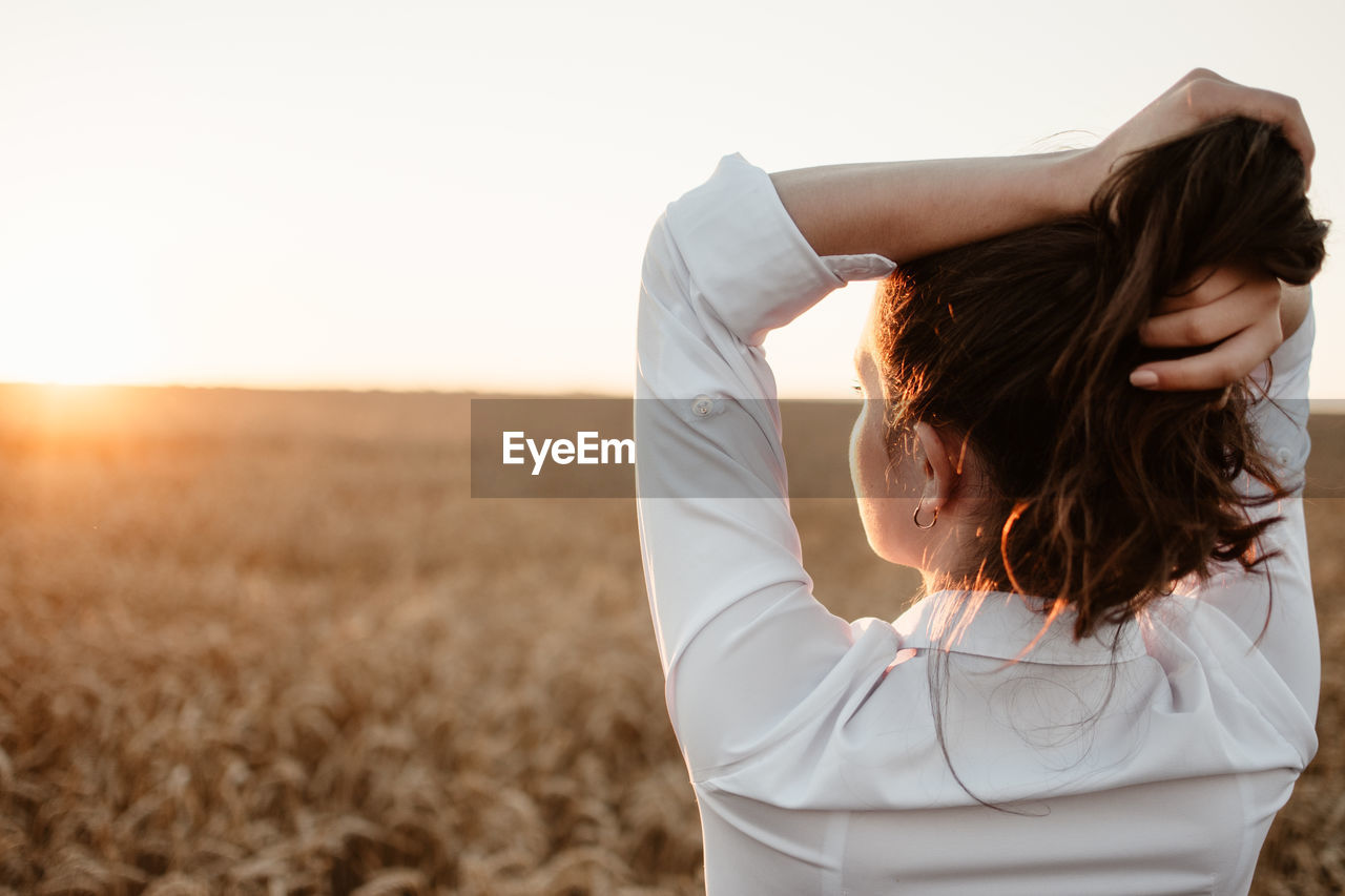 Rear view of woman standing on land against sky