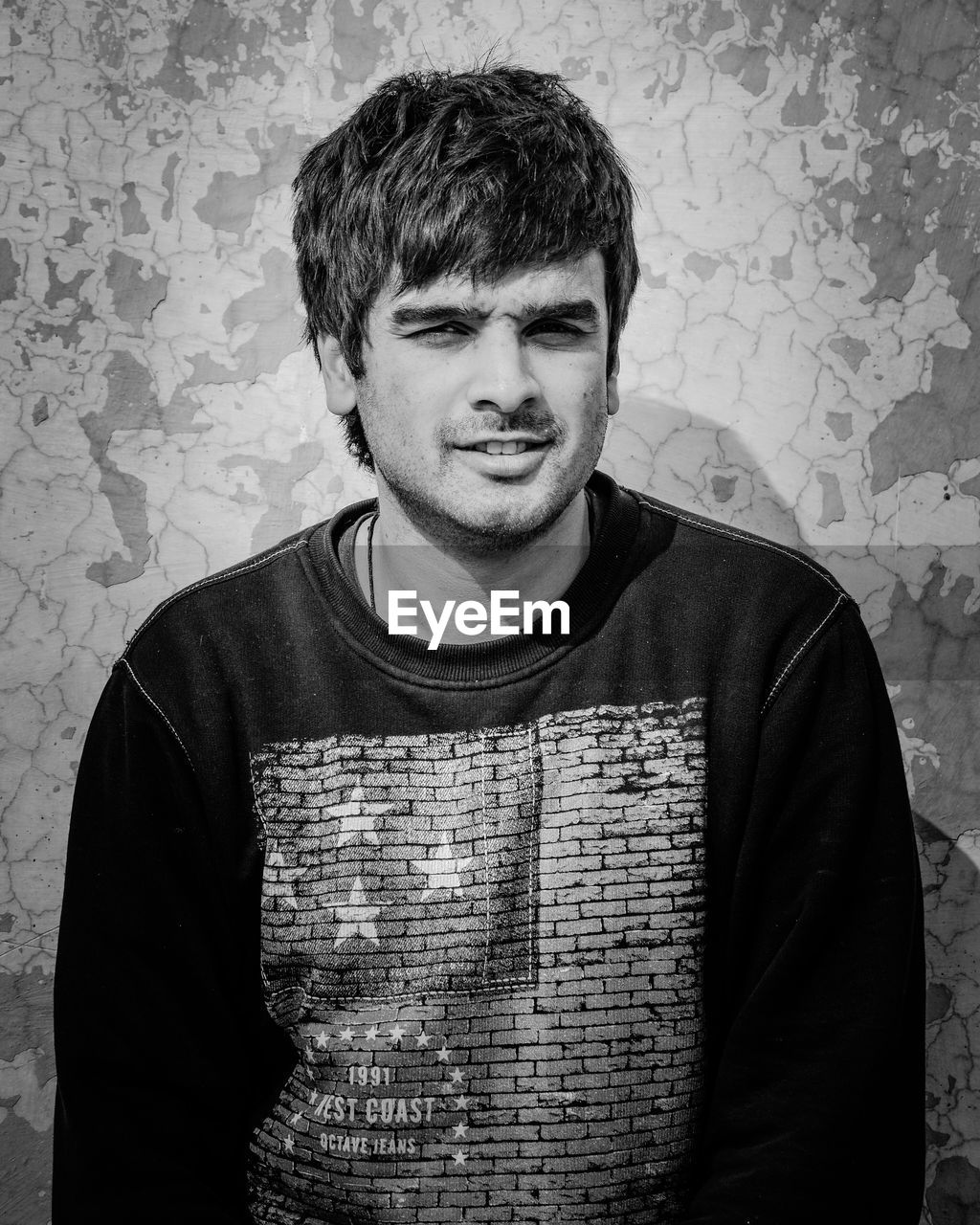 PORTRAIT OF MAN STANDING AGAINST BRICK WALL