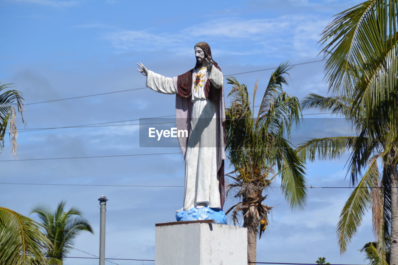 LOW ANGLE VIEW OF STATUE AGAINST PALM TREES
